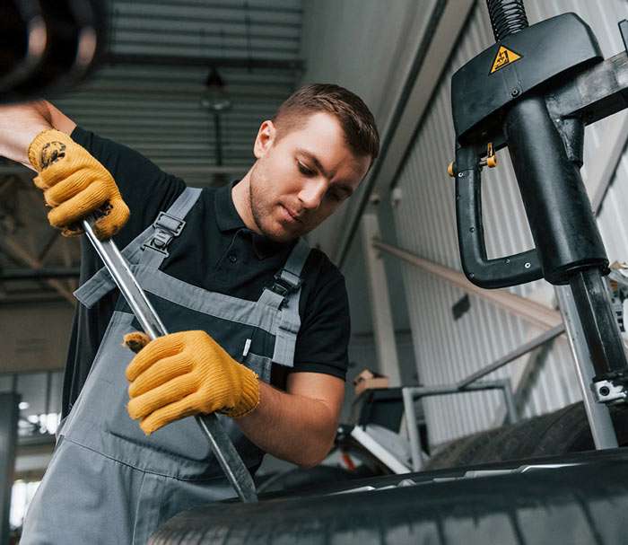 Meccanico che lavora sul vano motore di un'auto in officina